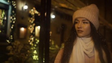 Vitrinler, yakınındaki sokakta yürürken güzel çekici kız çelenk ile dekore edilmiş ve ve vitrinler bakın. Yeni yıl Noel. Akşam çekim