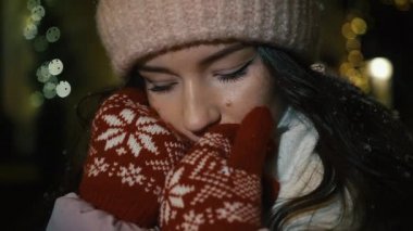 Güzel çekici kız bir window-shop ayakta çelenk ile dekore edilmiş ve kameraya bakıp. Yeni yıl Noel. Silah, ağır çekim, kar yağışı akşam