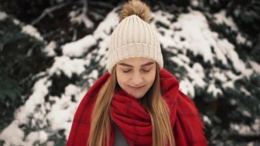 Noel ağaçları yürüyüş ve kameraya doğru seyir sıcak giysiler içindeki genç güzel kız içinde. Ağır çekim. Bir kış parkta şık genç güzel kız portresi