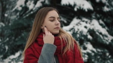 Noel ağaçları yürüyüş ve kameraya doğru seyir sıcak giysiler içindeki genç güzel kız içinde. Ağır çekim. Bir kış parkta şık genç güzel kız portresi