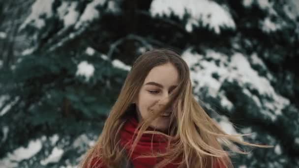 Närbild av en ung vacker flicka i varma kläder står nära de julgranar med långt hår skakar hennes huvud. Slow motion — Stockvideo