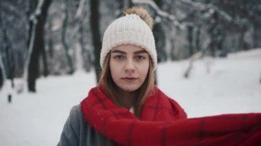 Noel ağaçları yürüyüş ve kameraya doğru seyir sıcak giysiler içindeki genç güzel kız içinde. Kız bir eşarp. Ağır çekim. Bir kış parkta şık genç güzel kız portresi