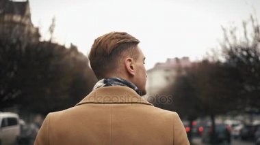 bir bulutlu havalarda sokakta yürürken bir pelerin genç bir işadamı. Ağır çekim