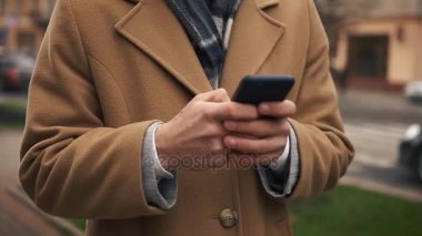 Smartphone kullanarak ve sokak, ağır çekimde yürüyen bir genç işadamı mutlu