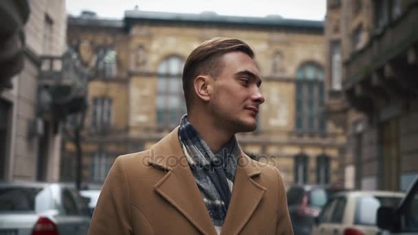 Ein junger Geschäftsmann in einem Mantel, der bei trübem Wetter die Straße hinunterläuft. Zeitlupe — Stockvideo