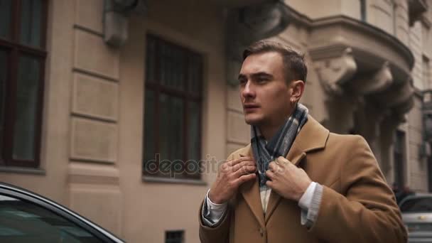 Młody biznesmen w płaszcz idąc ulicą przy pochmurnej pogodzie. Człowiek idzie na ulicy i sukienki. Zwolnionym tempie — Wideo stockowe