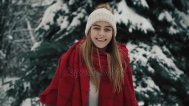Noel ağaçları yürüyüş ve kameraya doğru seyir sıcak giysiler içindeki genç güzel kız içinde. Ağır çekim. Bir kış parkta şık genç güzel kız portresi