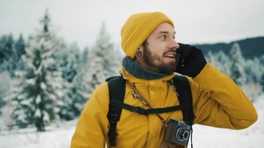Sakallı, telefonda konuşurken sarı kış giysileri giyen adam. Bir sırt çantası ile kış dağlarda bir uzun yürüyüşe çıkan kimse gider. Kış zamanında güzel dağlar