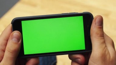 Yatay smartphone ile yeşil ekran kullanan adam. Yakın çekim çekim cep telefonu ile el mans. Chroma anahtar. Yakın çekim. Yatay