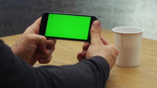 Homme utilisant un smartphone horizontal avec écran vert. Gros plan des mains de mans avec un téléphone portable. Clé chromatique. Ferme là. Horizontal — Video