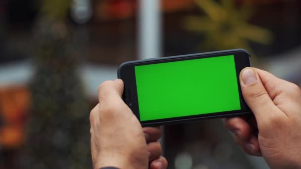 Homme utilisant un smartphone horizontal avec écran vert. Gros plan des mains de mans avec un téléphone portable. Clé chromatique. Ferme là. Horizontal — Video