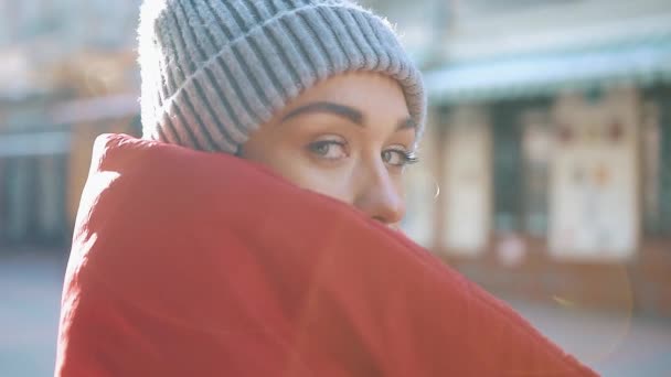 Sol brilla sobre una chica con chaqueta roja de invierno de pie en la calle — Vídeo de stock