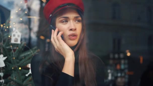 Mujer feliz habla por teléfono sentado en un acogedor café en frío día de invierno — Vídeos de Stock