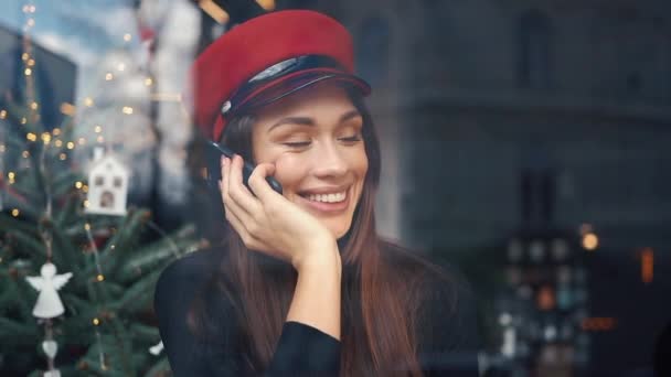 Щаслива жінка говорить по телефону, сидячи в затишному кафе в холодний зимовий день — стокове відео