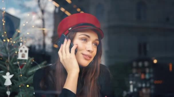 愉快的妇女谈话在电话坐在一个舒适的咖啡馆在寒冷的冬天天 — 图库视频影像
