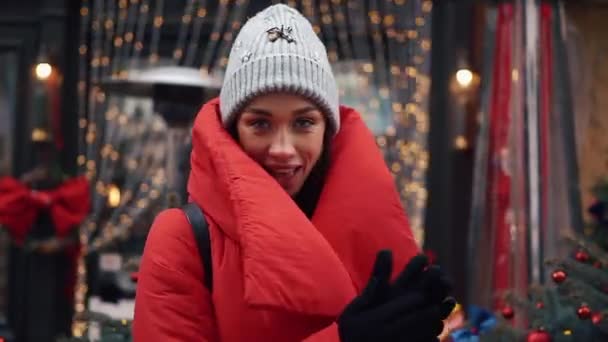 Lächelnde Frau tanzt vor einer Tür mit weihnachtlichem Dekor auf der Straße einer alten Stadt — Stockvideo