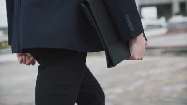 Man in zwart pak loopt met een map — Stockvideo