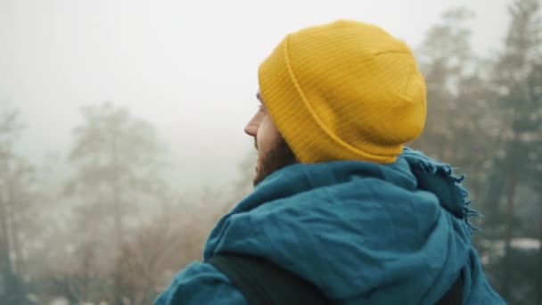 Man looks around himself standing on the top of the rock in the mountains covered with fog — Stock Video