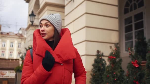 Όμορφη γυναίκα στο κόκκινο χειμερινό μπουφάν περίπατος κατά μήκος του δρόμου που καλύπτονται με χιόνι σε όμορφη παλιά πόλη της Ευρώπης — Αρχείο Βίντεο