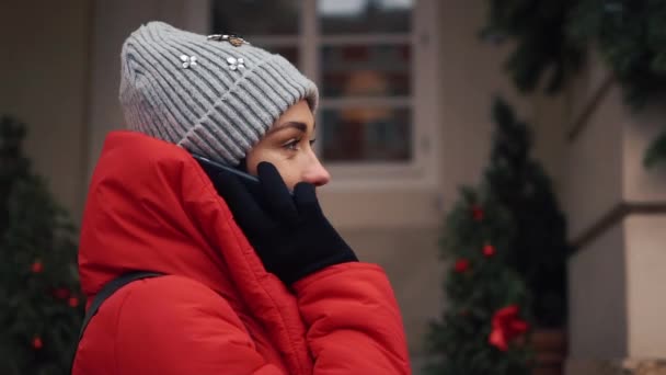 Όμορφο κορίτσι στο κόκκινο σακάκι συνομιλίες σχετικά με το smartphone στέκεται στον δρόμο σε ένα φωτεινό χειμωνιάτικη μέρα — Αρχείο Βίντεο