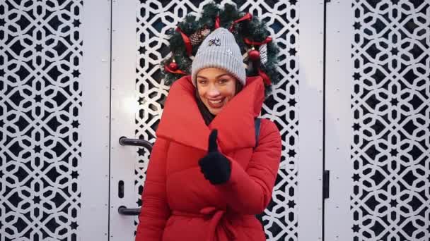 Lycklig kvinna i röda jackor väntar innan vita grindar utanför — Stockvideo