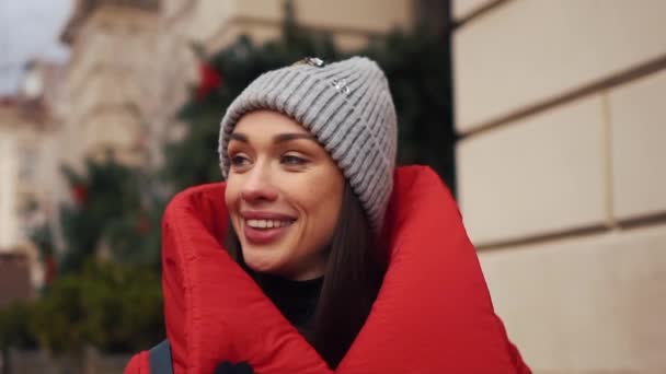 美丽的妇女穿着红色的冬季夹克沿着街道覆盖着雪在一个美丽的旧欧洲城市 — 图库视频影像