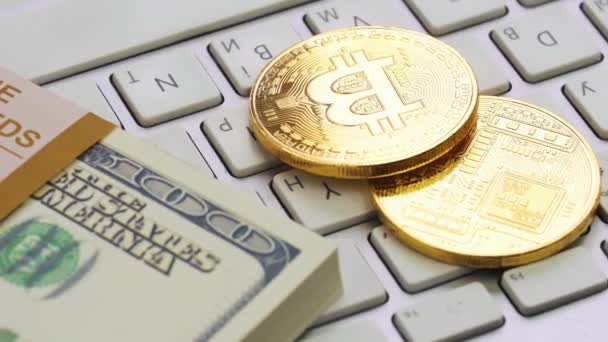 Goldene Bitcoins und Dollar liegen auf der weißen Tastatur — Stockvideo