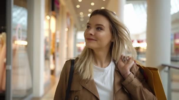 Mujer rubia feliz sonríe caminando con bolsas de compras alrededor del centro comercial — Vídeos de Stock