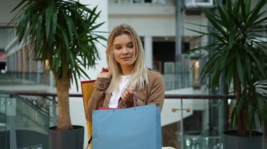 Kız alışveriş merkezinde ayakta omuzları üzerinde alışveriş torbaları tutar