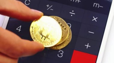 Adam altın bitcoins tek tek bir hesap makinesi üzerinde bir smartphone koyar.