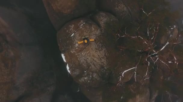 Hombre feliz con chaqueta amarilla gira en la parte superior de las rocas cubiertas de niebla — Vídeo de stock