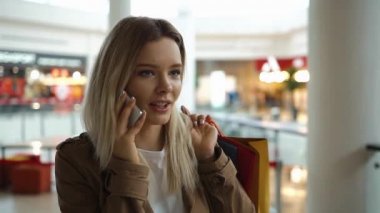 Alışveriş merkezinde alışveriş torbaları ile telefon ayakta mutlu sarışın kadın görüşmeler