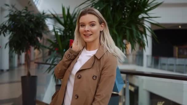 Regardez par derrière une jolie femme marchant avec un sac à provisions et tourbillonnant dans un centre commercial — Video