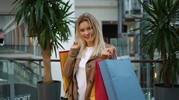 Fille tient des sacs à provisions sur ses épaules debout dans le centre commercial — Video