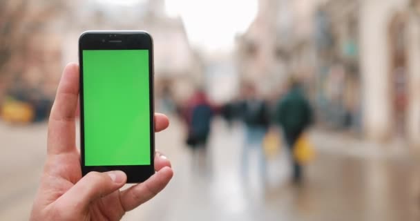 Close-up de mãos masculinas segurando smartphone ao ar livre no centro da cidade. Fecha. Movimento de localização. Chave Chroma. Hora da Primavera. Vertical. Filmado em câmera de cinema vermelho em 4K — Vídeo de Stock