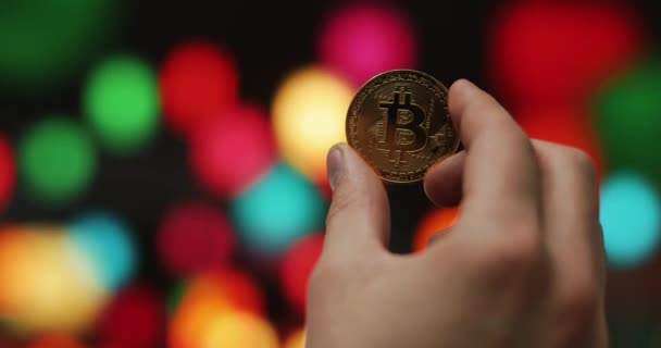 Man hands holding golden crypto currency BTC Bitcoin coins on a blurred colored background — Stok Video