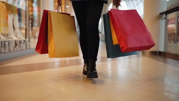 Mulher loira jovem caminha com sacos de compras coloridos em torno de um shopping — Vídeo de Stock