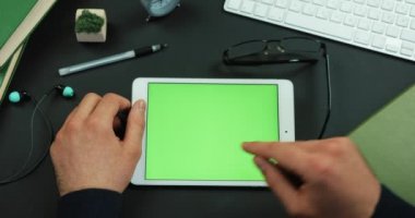 Tablet yeşil ekran ile çalışma tablosu üzerinde yatıyor ve üzerine bir şeyler adam musluklar