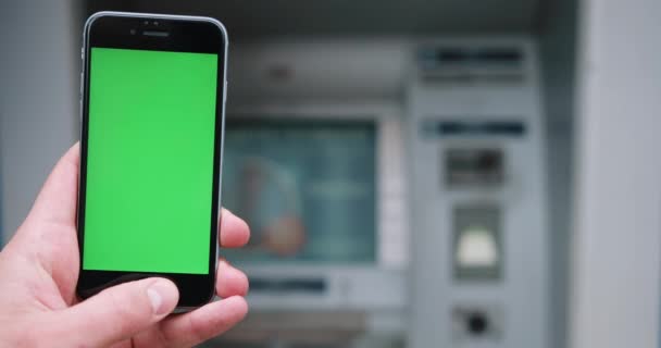 Primer plano de la mano sosteniendo un teléfono inteligente con pantalla verde en la calle. Clave de croma. Vertical. Fotografía en la cámara de cine RED en 4K — Vídeos de Stock