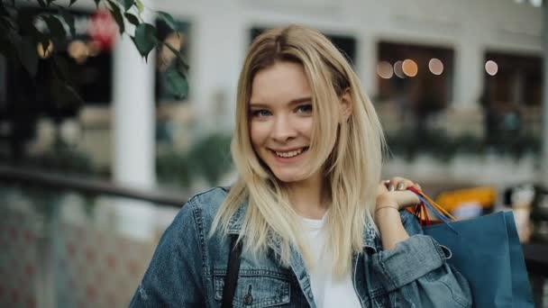 Charming girl poses with colorful shopping bags in the mall — Stock Video