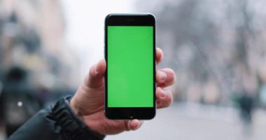 Kar düşüyor bir el ile yeşil perde smartphone onun kolundan tutarak mans