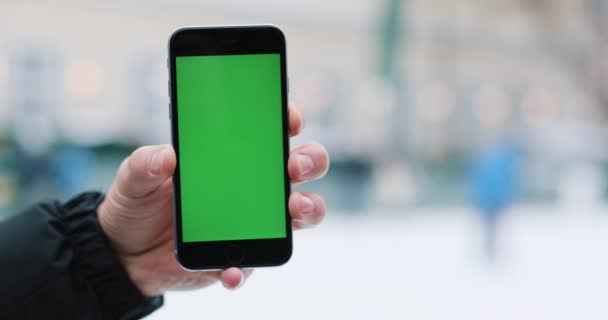 Śnieg pada mans ręki trzymającej smartphone z zielonym ekranem w jego ramię — Wideo stockowe