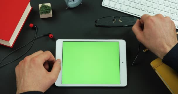 Hombre pone sus gafas por la tableta con pantalla verde sobre la mesa — Vídeos de Stock