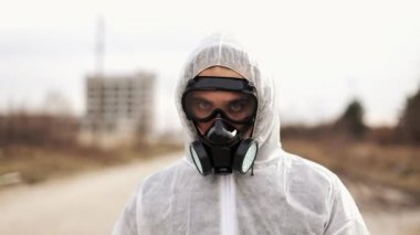 Koruyucu kostüm ve solunum gaz maskesi virolog adam yürümek endüstriyel Fabrika arka plan, ıssız bir şehirde
