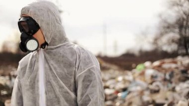 Koruyucu kostüm ve gaz maskesi respiratör yürüyen çöplük Site kirliliği, ekolojik felaket yakınındaki virolog adam