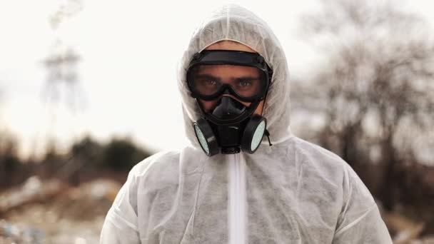 Hombre virólogo con disfraz protector y máscara de gas respirador mirando en cámara encendida en vertedero Contaminación, Desastre ecológico — Vídeos de Stock
