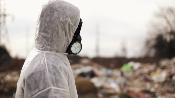 Вирусолог в защитном костюме и маске респиратора идет рядом с загрязнением свалки, экологическими катастрофами — стоковое видео