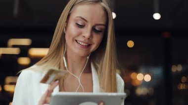 Gülümseyen genç kadın altın kredi kartı bir tablet ile çalışan bir veri alır