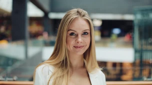Lächelnde junge blonde Frau sieht charmant aus, wenn sie ihre Haare für eine Kamera fixiert — Stockvideo