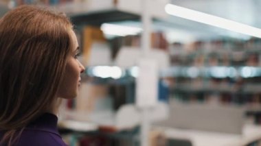 Kütüphane raflarında boyunca yürüyüş bir kız profil bakın